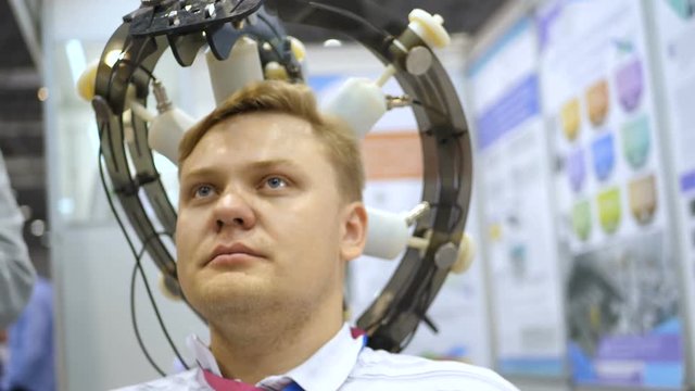 Man wired to an EEG machine or electroencephalograph which produces a graphical record of electrical activity of the brain. Young man set on his head. Electroencephalographic examination