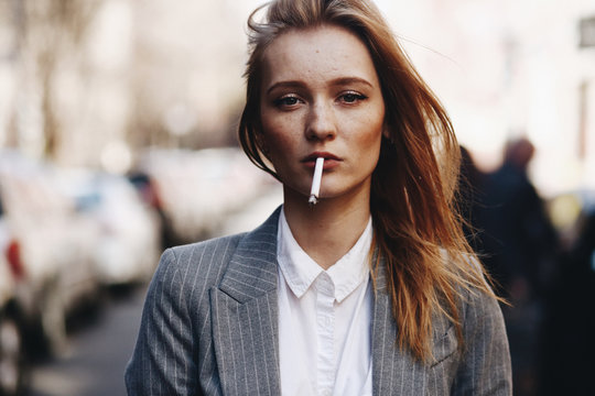 Blonde girl with cigar stands on the street