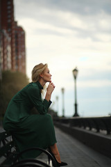 Thoughtful woman in green dress sits on the bench