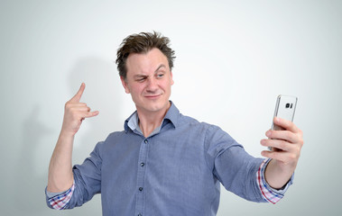Obraz na płótnie Canvas Funny man grimaces make selfie on a smartphone