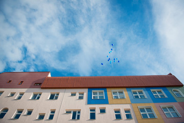 Fototapeta na wymiar Balloons blue colors flying in the blue sky with clouds near the building