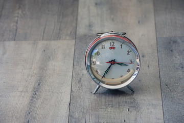 Time Management Concept : Close up red vintage alarm clock be distorted and damaged setting on wooden floor in vintage style.