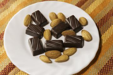 Chocolate and Almonds on a white dish. Color Background