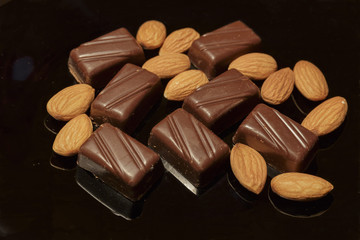 Chocolate and Almonds on a Black dish. Dark Background