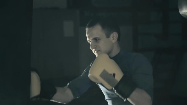 The athlete trains before the fight. A boxer punches the heavy bag. Black background