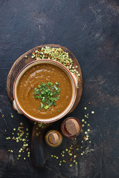 South asian cream-soup with dried green split peas and curry. Flat-lay with space on a dark brown stone surface