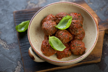 Bowl of baked beef meatballs in tomato sauce, selective focus, studio shot