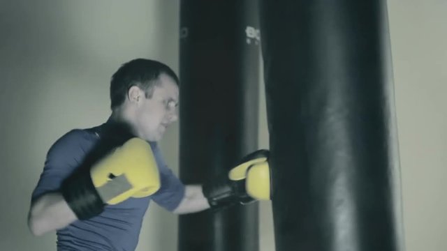 The athlete trains before the fight. A boxer punches the heavy bag. Black background