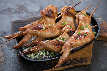Metal plate with bbq chicken wings on skewers, selective focus, studio shot