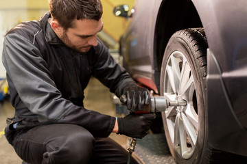 Fototapeta na wymiar auto mechanic with screwdriver changing car tire