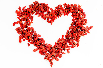 Dried goji berries in heart shape on white background top view copyspace pattern