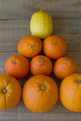 Vertical photo of citrus fruits: lemon, orange and tangerine on wooden board