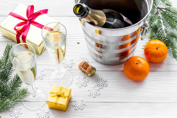 Fototapeta na wymiar Champagne for celebrate New Year 2018. Glasses, tangerine, spruce branch on white wooden background copyspace