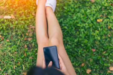 Beautiful Young asian woman smiling while reading her smartphone in garden. Portrait of asian women reading message with smart phone in park outdoor.