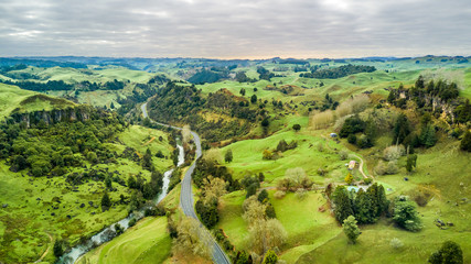 Aerial view on a road running along a river through mountain valley with rocks on the background. Taranaki region, New Zealand