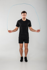 Strong young sports man jumping with skipping rope