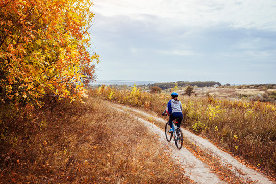 Young woman riding a bicycle in the autumn field