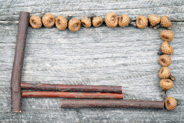 Still life composition/ frame with tiny acorns and wooden sticks on an old wooden surface. Beautiful vintage composition