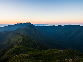 Fototapeta na wymiar The valley of two ranges of mountain ridge at Doi Phu Wae in Nan, Thailand. The place is surround by green nature with the morning sunrise sky behind