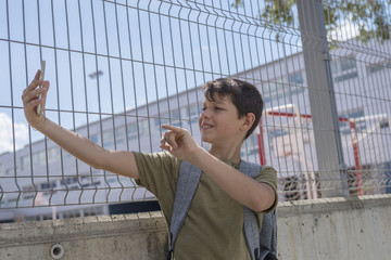 Student resting outside a school and playing with a mobile phone