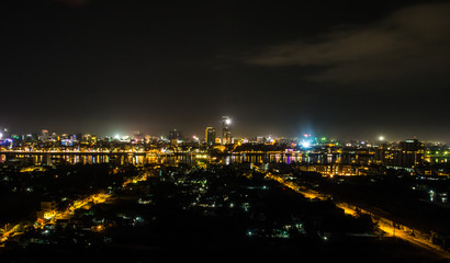 Fototapeta na wymiar Night cityscape photo of Phnom Penh, the capital city of Cambodia. The yellow street light grow perspectively in both side leading to a long way reflection light at the river