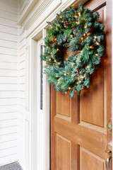 Lighted Christmas wreath on a home's wooden front door