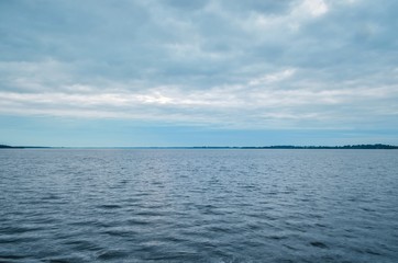 Obraz premium Minimalist summer landscape. Large lake with coastline on a cloudy day.