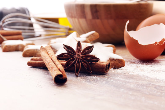 Baking ingredients for homemade pastry on wooden background with cookies and spieces.