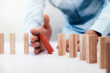 Businessman hand stop dominoes continuous toppled or risk with copyspace. Risk, Strategy, Planning management concept.