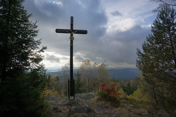 Crucifix high above sea level, surrounded by trees and clouds.