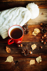 Mug of hot coffee in a woman's hand in a sweater in the autumn setting on a wooden table with a knitted scarf, sweater. Comfort, warmth, cozy