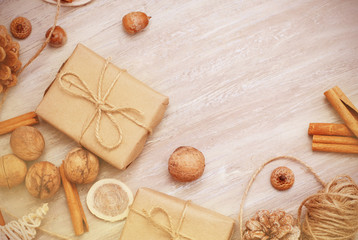 Kraft Paper Gift box with ribbon bow from above, cinnamon, nuts and wire on rustic white background
