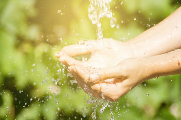 Woman washing hand outdoors. Natural drinking water in the palm. Young hands with water splash, selective focus. Instagram filter