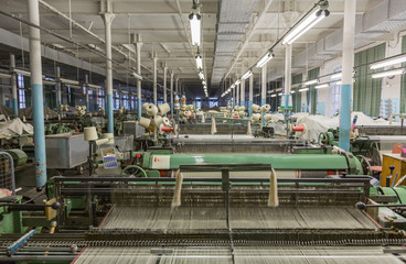 Weaving factory's workshop with old equipment and machine tools
