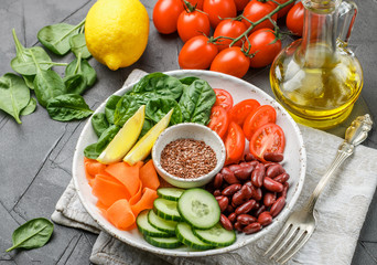 Vegetarian buddha bowl. Raw vegetables - tomatoes, cucumbers, beans, spinach, carrots, lemon and flax seed in a bowl. healthy, detox food concept. Selective focus
