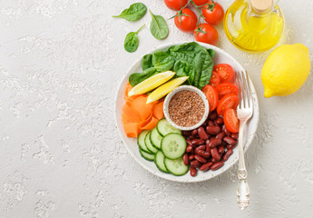 Vegetarian buddha bowl. Raw vegetables - tomatoes, cucumbers, beans, spinach, carrots, lemon and flax seed in a bowl. healthy, detox food concept. Selective focus. Top view, Copy space