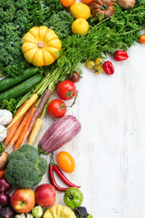 Top view of fresh raw vegetables, fruits and herbs on wooden white background, copy space for text, selective focus