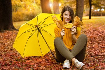 happy woman with umbrella walking in autumn park
