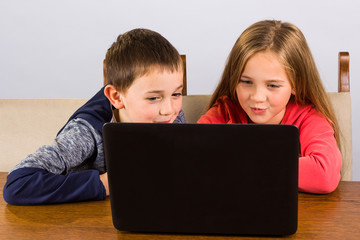 Little boy and girl having fun on a laptop computer