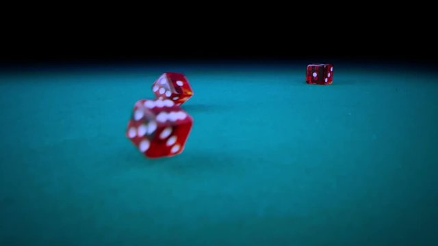 three red dice rolling on green game gambling table on black background, shooting with slow motion, concept of sport recreation leisure game in the casino