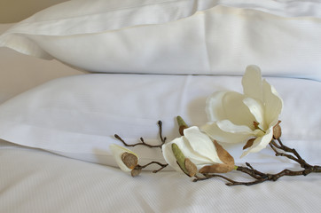 Two pillows in white cases and artificial orchids beside them