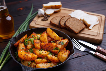 Countryside homemade traditional food, roasted potatoes, bacon, rye bread on dark wooden table. Home food
