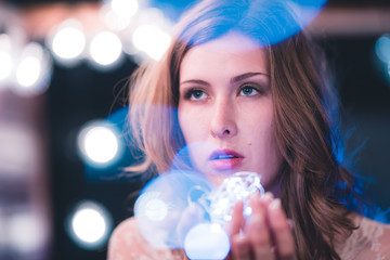 Attractive young caucasian woman poses with string lights with heavy bokeh