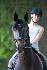 Obraz premium Portrait of black horse with teenage girl equestrian on it