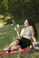 Joyful time of a young beautiful woman having a picnic, wearing a skirt and a sexy deep neckline...