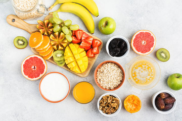 Healthy breakfast with oats, variety of fruits, strawberries, mango, grapes, figs, yogurt and nuts served on the white table, above, selective focus