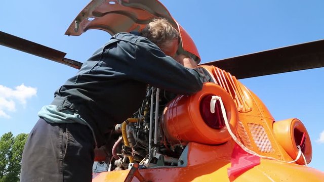 The worker twists the nuts in the engine.