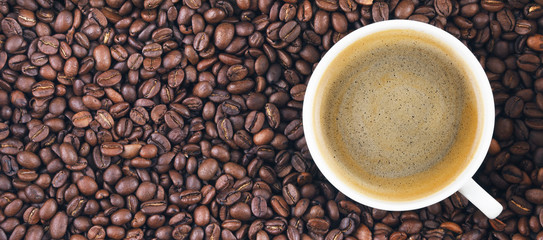 Fried coffee beans. Coffee mug on the background of coffee beans. Panorama, banner.