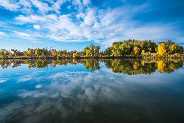 Fototapeta premium Reflection of autumn trees and clouds at the lake