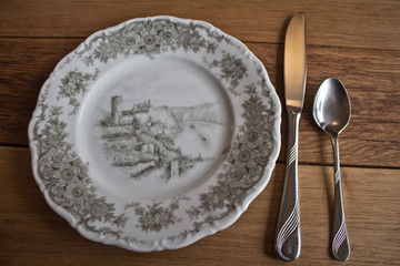 Handbemaltes Porzellan Teller mit Besteck auf einem Massiven Holztisch Hintergrund